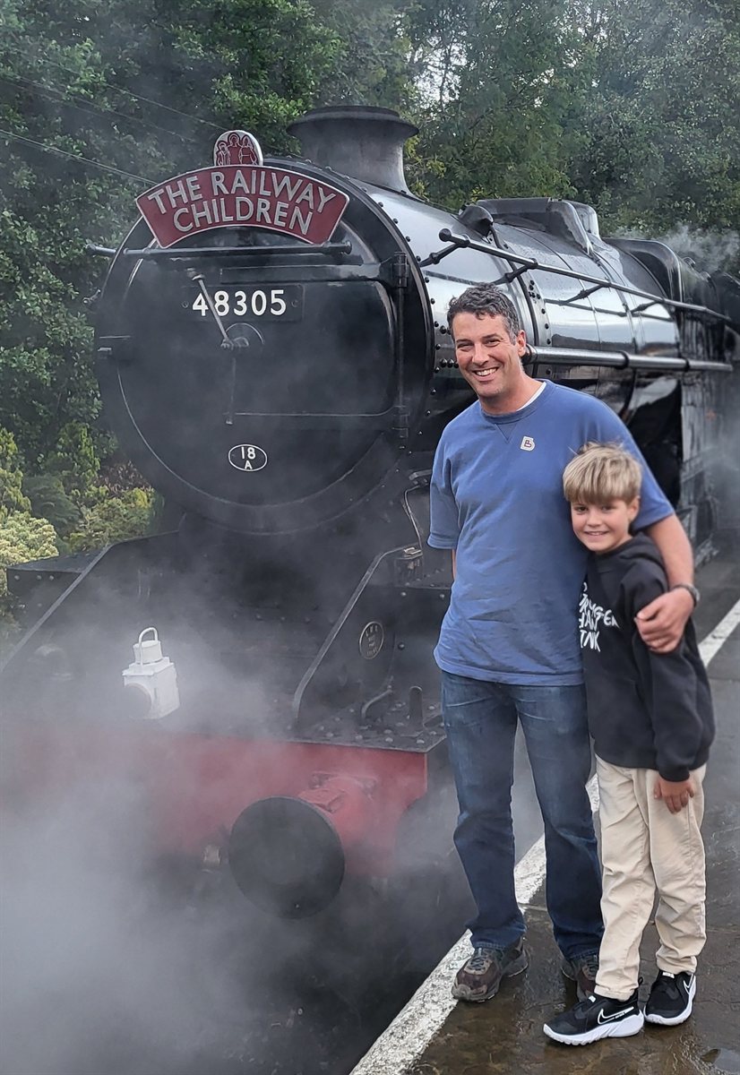 Matt with his son in front of a steam locomotive
